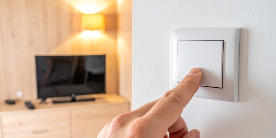 una mano pulsando un interruptor de la luz